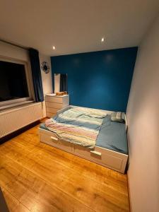 a bedroom with a bed with a blue wall at Villa Brussel in Dilbeek