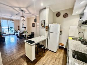 a kitchen with a white refrigerator and a table at The Best in Camba Cua, A metros de la costanera y del centro de la ciudad, ubicacion inmejorable, cerca de la playa, a 2 cuadras parque Cambacua dpto moderno, completamente equipado, con balcon, con todo lo necesario para una estadia comoda y placentera in Corrientes