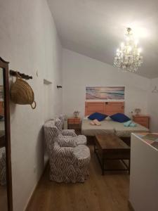 a bedroom with a bed and a chair and a chandelier at La madrileña 2 in Casabermeja