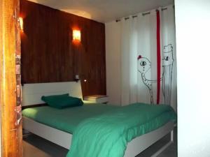a bedroom with a green bed with a drawing on the wall at Côté Montagne in Orcières