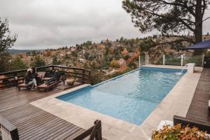 a couple sitting on benches next to a swimming pool at Cabañas del Peñón in La Cumbrecita