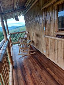 a porch of a cabin with two chairs on it at Finca Maashaven in Mediacanoa