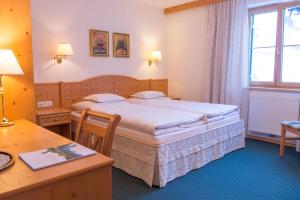 Una habitación de hotel con una cama grande y un escritorio. en Das Bürstegg, en Lech am Arlberg