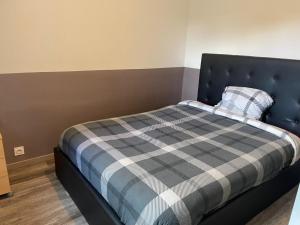 una camera da letto con un letto con una coperta a quadri di Petite maison cosy au fond du jardin a Belle-Église