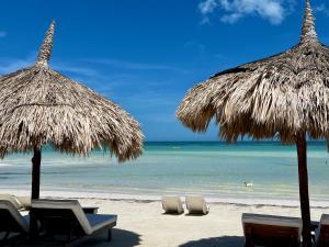 two straw umbrellas and chairs on a beach at Palapas del Sol in Holbox Island