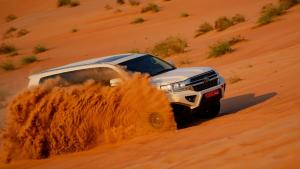 a white truck driving in the desert at Infinity Camp in Bidiyah
