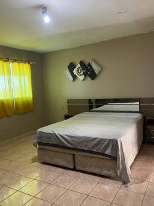 a bedroom with a bed and a yellow window at Linda casa em Enseada dos Corais in Cabo de Santo Agostinho