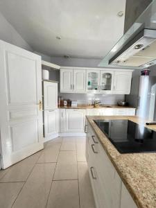 a kitchen with white cabinets and a black counter top at Villa d'architecte 4 chambres 9 Personnes Proche Disney Paris in Le Perreux-Sur-Marne