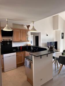 Una cocina con gabinetes de madera y una encimera negra. en Appartement clim & piscine sur Golf, en Pont-Royal