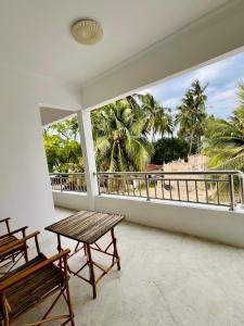 a balcony with a table and a view of palm trees at Tumbo Swahili Villa in Gulioni