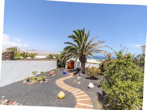 a garden with a gravel pathway with a palm tree at Casa Susanne in Famara