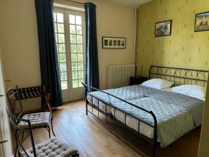 a bedroom with a bed and a chair and a window at Villa Moncoeur in Remiremont