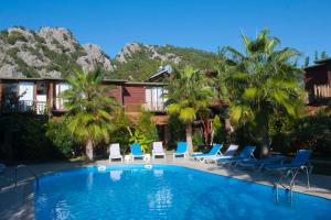 a resort pool with chairs and palm trees at Kutle Hotel in Cıralı