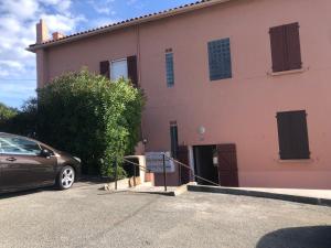 a car parked in front of a pink building at Charmant petit appartement vue mer et corniche Esterel in Anthéor