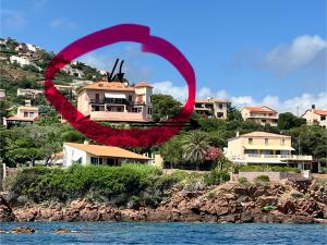 a red circle with a house on a hill next to the water at Charmant petit appartement vue mer et corniche Esterel in Anthéor