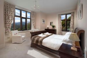Un dormitorio con una cama y una silla y ventanas. en Brunt How, en Ambleside
