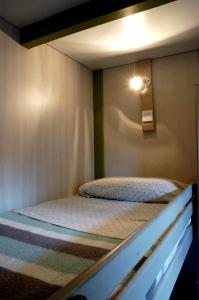 a bed in a room with a light on the wall at Camping As Cancelas in Santiago de Compostela