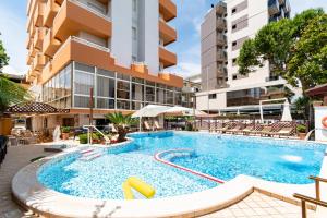 an outdoor swimming pool with chairs and a building at HOTEL BALTIC in Alba Adriatica