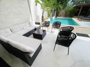 Luxury House Tomanoa - 10pers - 4rooms - Pool - HotJacuzzi - Speed Wifi -waterfall في تولوم: فناء مع أريكة وكراسي بجوار حمام سباحة