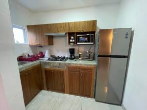 a kitchen with a stainless steel refrigerator and wooden cabinets at Mini Casita, around nature in Santa Cruz de la Soledad