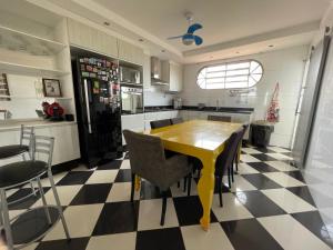 a kitchen with a yellow table and black and white checkered floor at Apart. centro Ribeirão Hospital São Lucas in Ribeirão Preto