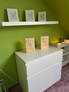 a white dresser against a green wall with shelves at Harzlicht Braunlage - mit Balkon und Weitblick in Braunlage