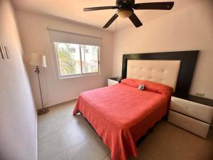 - une chambre avec un lit doté d'une couverture rouge et d'un ventilateur de plafond dans l'établissement Residencial Terrasol, à Acapulco