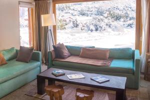 a living room with a couch and a table and a window at Galileo Boutique Hotel in San Carlos de Bariloche