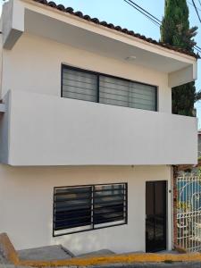 a white house with black windows at Tranquila casa in Mexico City