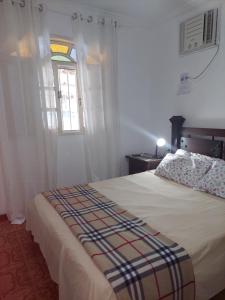 ein Schlafzimmer mit einem Bett und einem Fenster in der Unterkunft Casa Bonita Rio das Ostras, ar condicionado, wifi, churrasqueira e garagem in Rio das Ostras