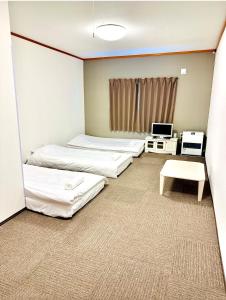 a room with three beds and a table and a tv at Pension Berg in Kutchan +38 photos
