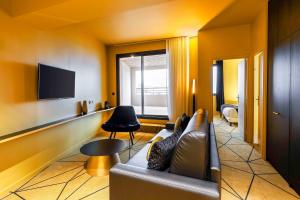 a living room with a couch and a tv at Hotel Leprince, Best Western Premier Collection in Le Mans