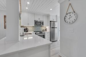 a kitchen with white cabinets and a clock on the wall at New listing - Condo on Harbor Island in St. Helena Island +18 photos