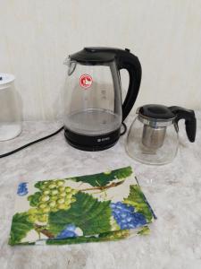 une théière noire et une assiette de raisins sur un comptoir dans l'établissement Минималистичная квартира, à Kyzylorda