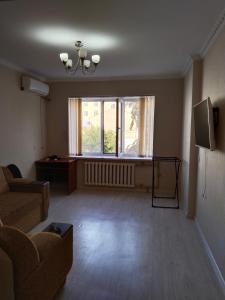 un salon avec un canapé, une table et une fenêtre dans l'établissement Минималистичная квартира, à Kyzylorda