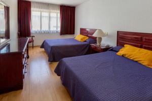 オアハカにあるHotel Gala Oaxacaのベッド2台とドレッサーがあるホテルの部屋
