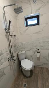 a white bathroom with a toilet and a window at Къща за гости Етерна - Guest house Eterna in Starosel