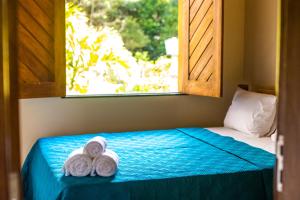two towels on a bed in a room with a window at Flats Brasil Itacaré in Itacaré