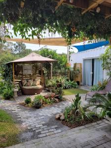 an outdoor patio with an umbrella and a couch at Moã do Mar Suítes in Guarda do Embaú