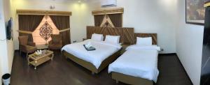 a hotel room with two beds and a chair at Dream Inn Guest House Islamabad in Islamabad