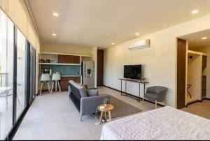 a living room with a couch and a kitchen at Chic Loft Steps from the Beach in Holbox Island
