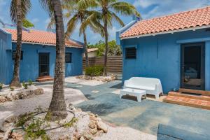 a blue house with palm trees and a white bench at Blue Bonaire by Boutique Bonaire Unique Resorts in Kralendijk