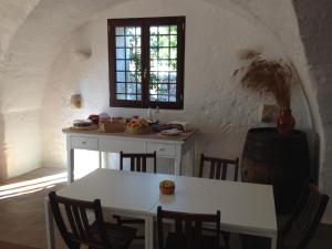 - une table et des chaises blanches dans une chambre avec fenêtre dans l'établissement Masseria Purgatorio, à Fasano