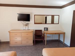 ein Schlafzimmer mit Kommode, Fernseher und Schreibtisch in der Unterkunft Hotel Coronado in Ensenada