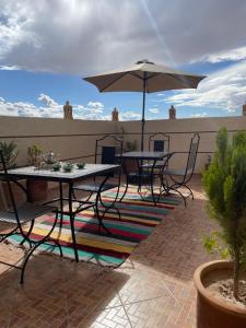a patio with two tables and an umbrella at Dar Mgouna Roses in Kalaat MGouna