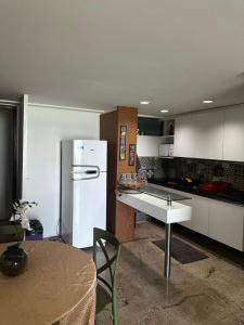 a kitchen with a white refrigerator and a table at Tamandaré Holiday Flat Beira-Mar Apartamento 107 in Tamandaré