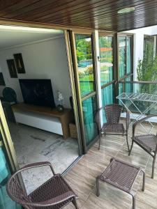 a screened porch with chairs and a table and a fireplace at Tamandaré Holiday Flat Beira-Mar Apartamento 107 in Tamandaré +26 photos