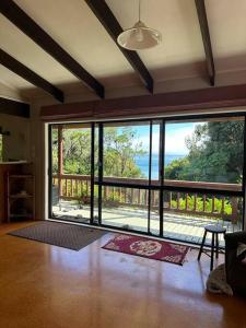 - un salon avec une grande porte en verre offrant une vue dans l'établissement Ōmāpere Bach, à Omapere