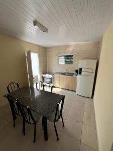 eine Küche mit einem Tisch mit Stühlen und einem Kühlschrank in der Unterkunft Refúgio da Camboa - Casa Menta in Governador Celso Ramos