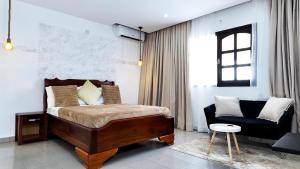 ein Schlafzimmer mit einem Bett, einer Couch und einem Stuhl in der Unterkunft Villa Kalm in Abidjan + 30 Fotos